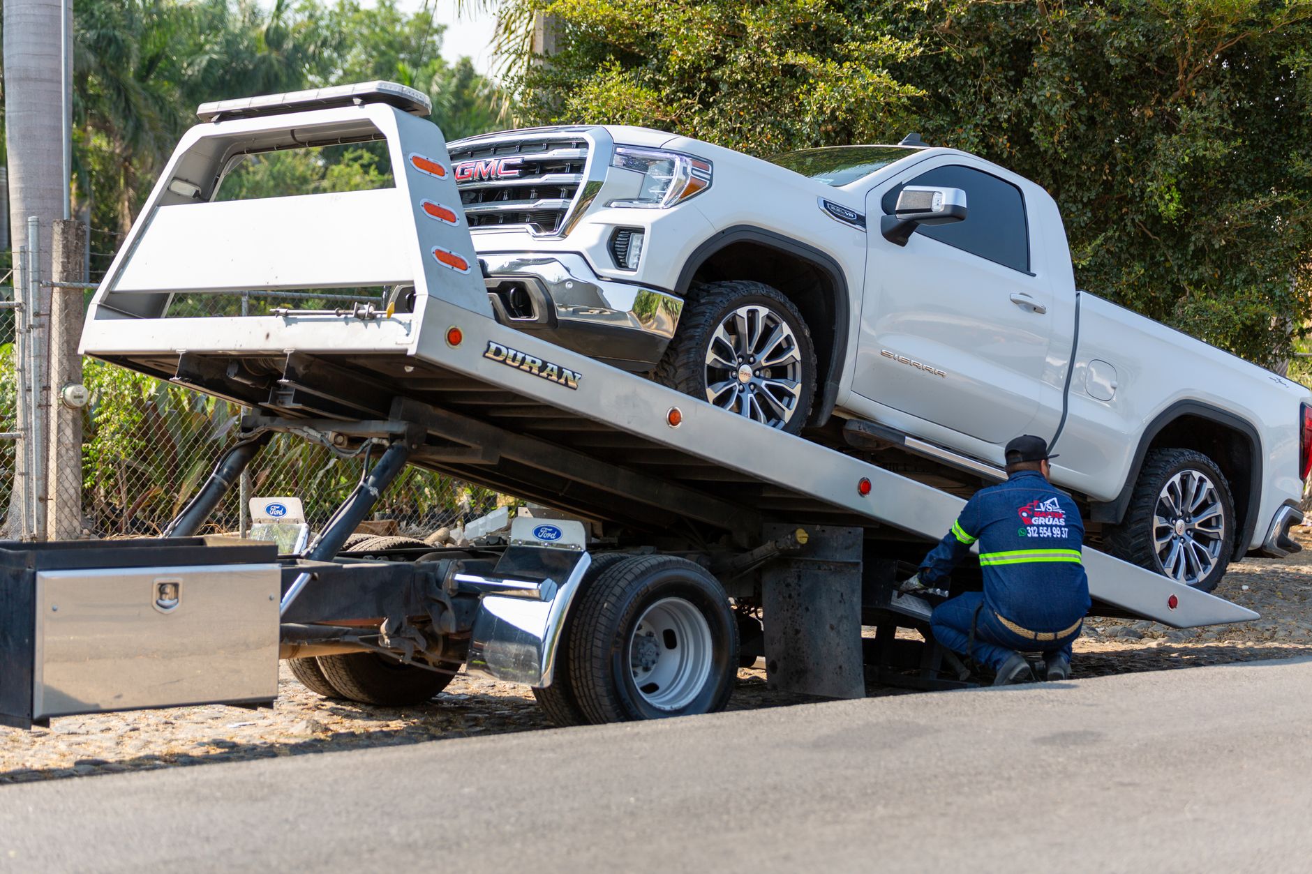A Snappy Towing professional assisting a motorist with a tire change on the side of a road in Port Allen, Louisiana, with safety cones around the vehicle.